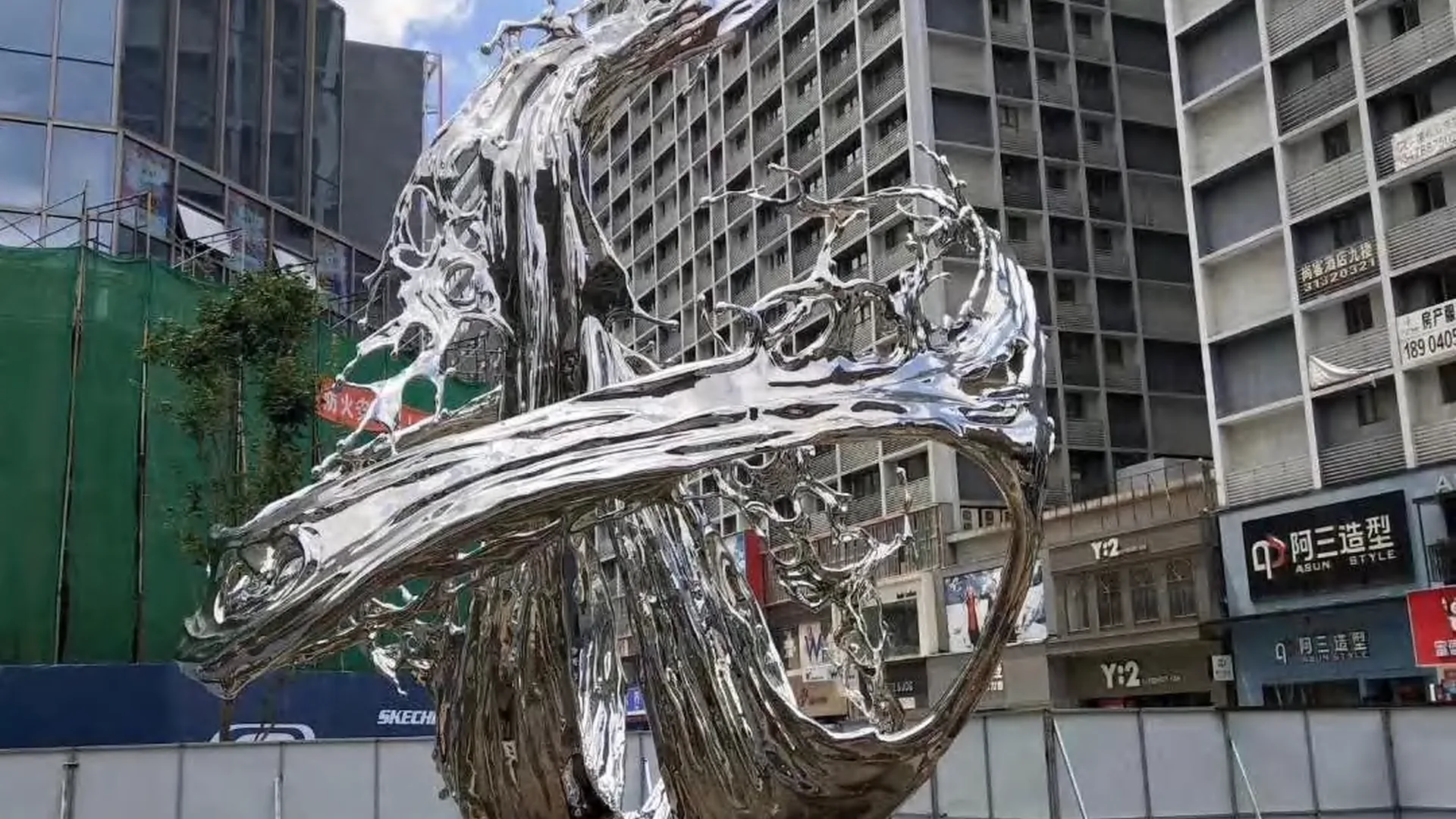 Large polished stainless steel abstract sculpture in an urban setting